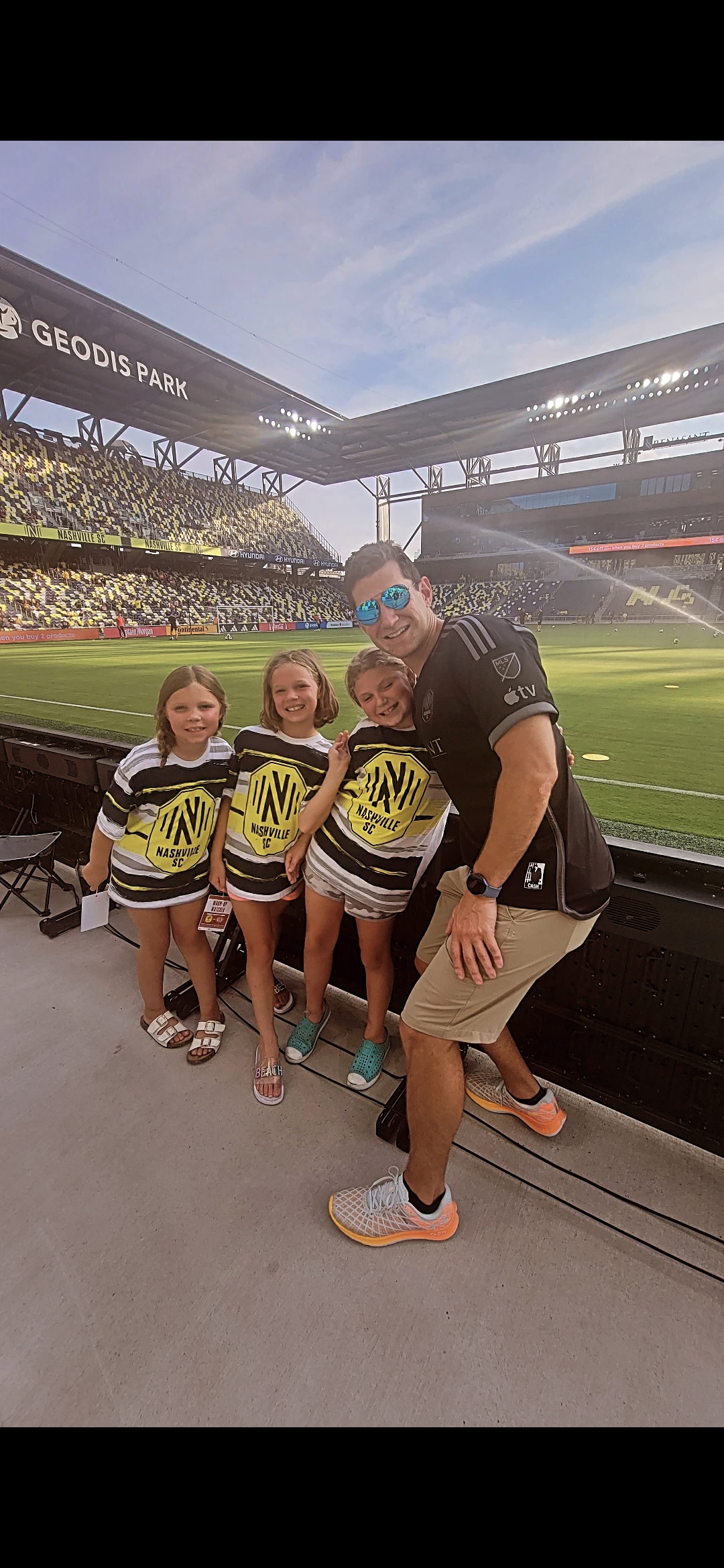 Father and three girls at soccer stadium